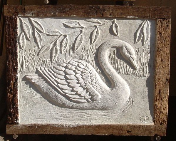 a carving of a swan on display in a wooden frame with leaves and branches around it