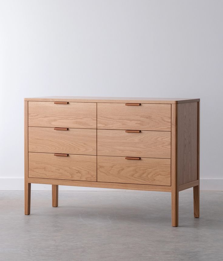 a wooden dresser sitting on top of a floor next to a white wall in an empty room