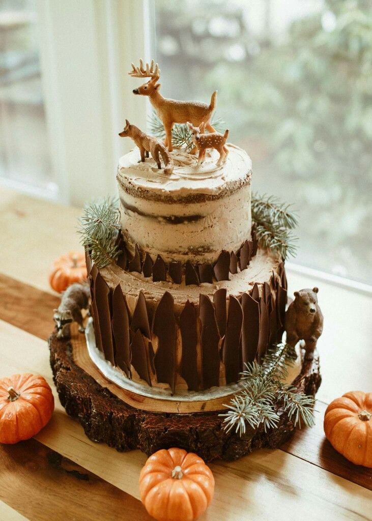 a three tiered cake with deer figurines on top and pumpkins around it