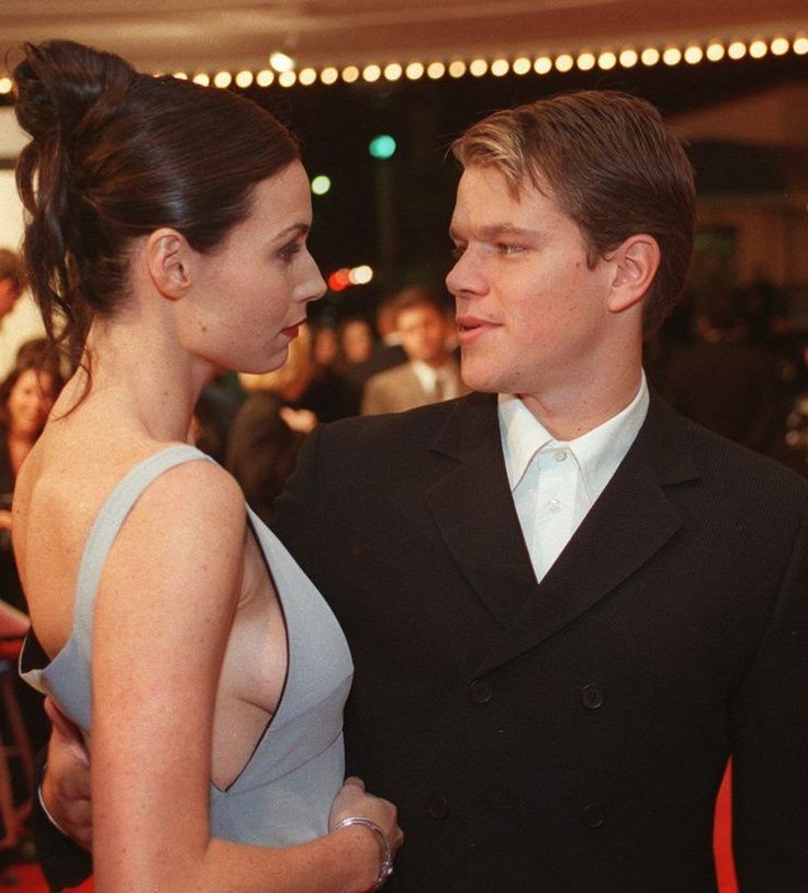 two people standing next to each other on a red carpet