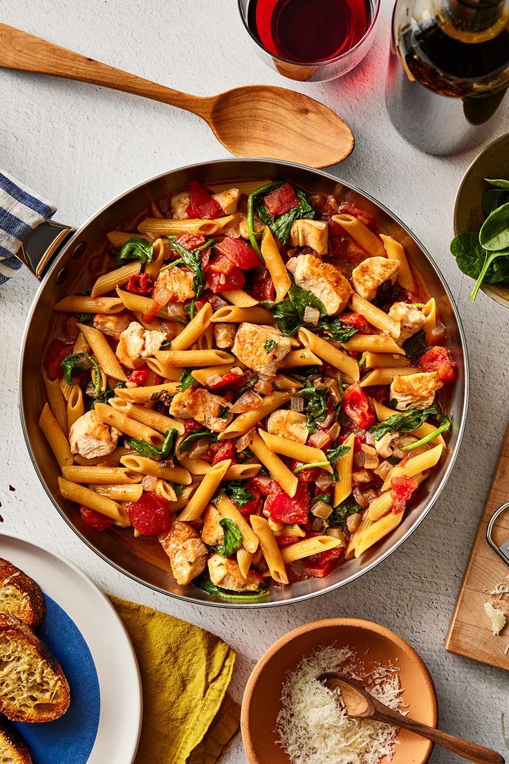 a pan filled with pasta and vegetables on top of a table next to other dishes