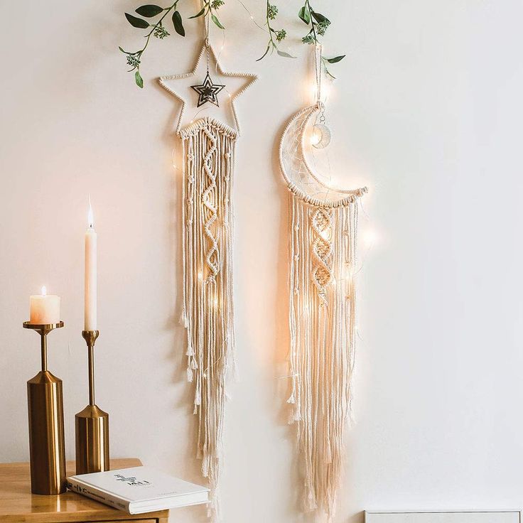 two white flowers are hanging on the wall next to some candles and other decor items