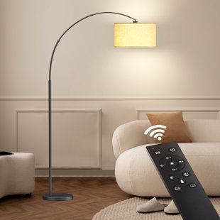 a remote control sitting on the floor in front of a white couch with a lamp