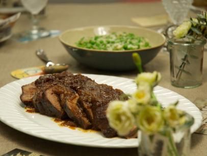 a plate with some meat on it and other dishes in the background at a dinner table