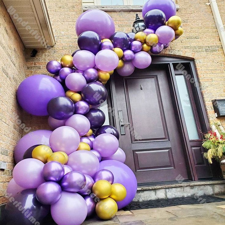 purple and gold balloons in front of a door on a brick building with an entrance