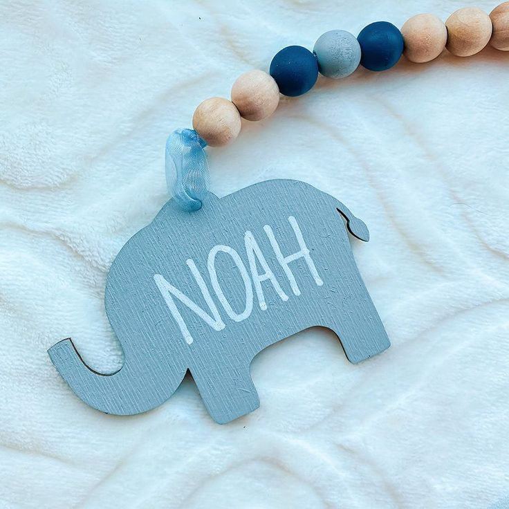 a wooden beaded necklace with an elephant and the word noah hanging from it's back