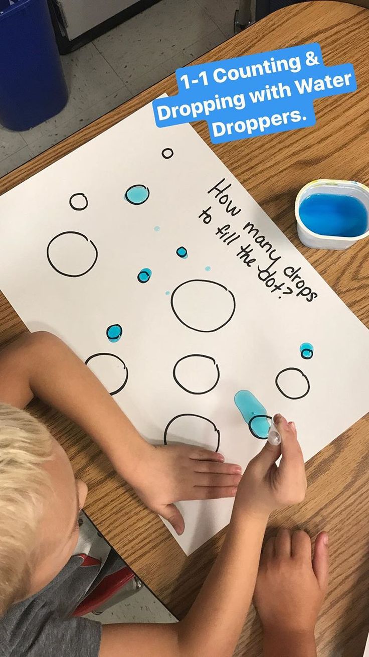 a young boy sitting at a table writing on a sheet of paper that says counting and dropping with water drops