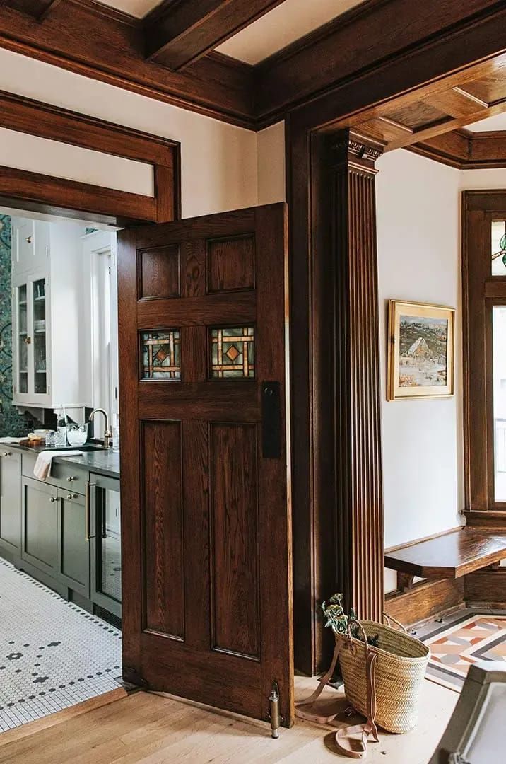 an open door leading to a kitchen and dining room with wood trimming on the walls