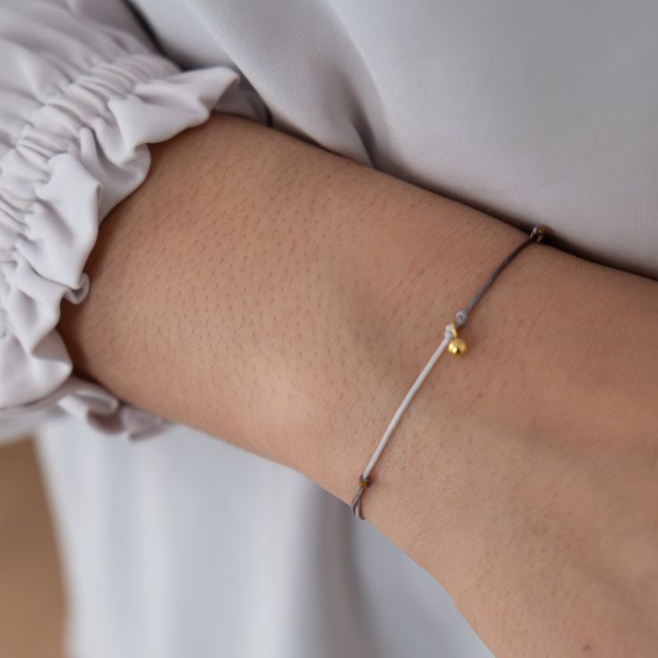 "Our Dainty Ball Bracelets are made with a strong nylon cord and a beautiful solid 18k gold ball charm.  A minimalistic design with a lasting effect.  These bracelets are great for gift giving as Friendship Bracelets or a minimalist everyday jewelry piece. Each bracelet is mounted on our gift cards marked 18k gold and packaged in our Vivien Frank gift box. Details: ✦ 18k solid gold ball charm ✦ charm approx 5mm ✦ Adjustable Nylon Cord ✦ water proof First image is of ombre - tones of grey If you Adjustable Minimalist Gold Bracelet For Gift, Adjustable White Gold Bracelet For Everyday, Elegant Adjustable Friendship Bracelets As Gift, Elegant Adjustable Cord Friendship Bracelets As Gifts, Modern Adjustable White Gold Bracelet, Elegant Bracelets With Adjustable Cord For Gifts, Minimalist Yellow Gold Braided Bracelets As Gift, Elegant Adjustable Cord Bracelets As Gift, Elegant Adjustable Cord Bracelet For Gifts