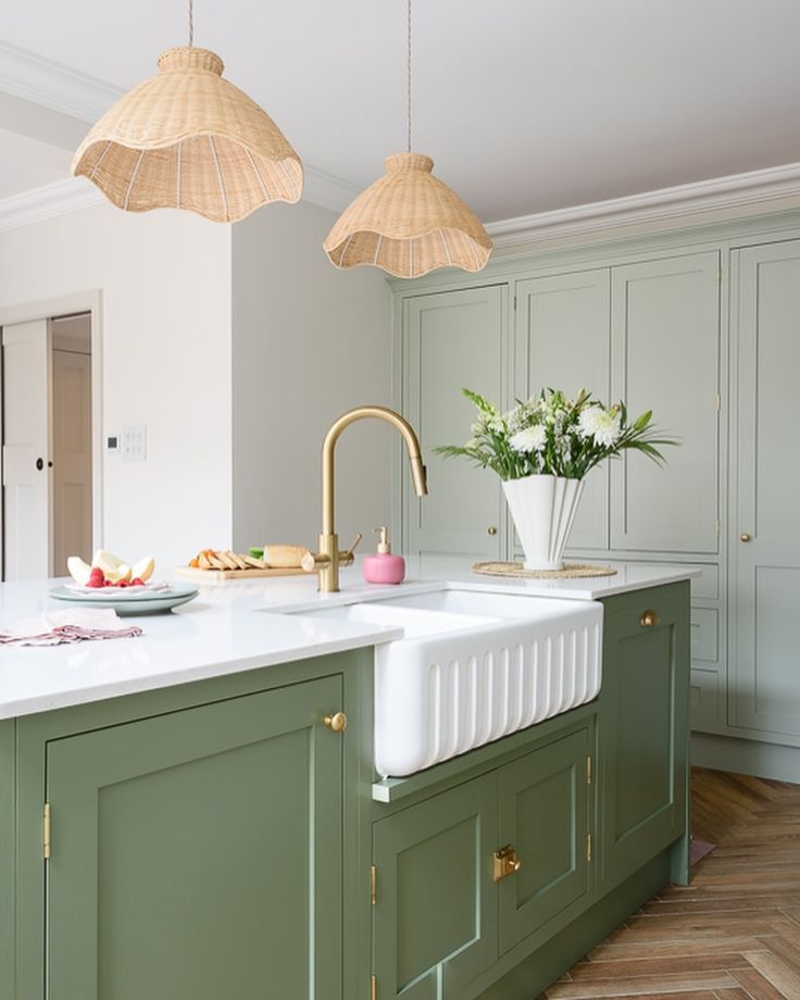 a kitchen with green cabinets and white counter tops, gold faucets hanging from the ceiling