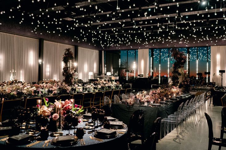 a banquet hall with tables and chairs covered in lights