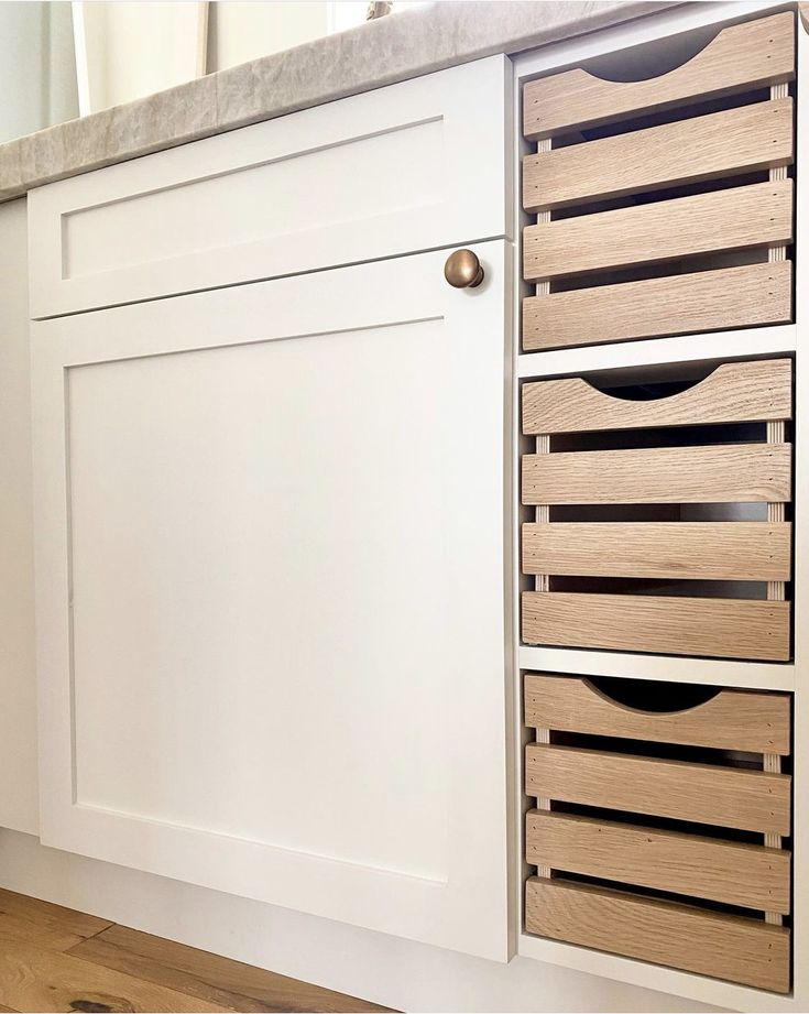 a kitchen with white cabinets and wooden drawers