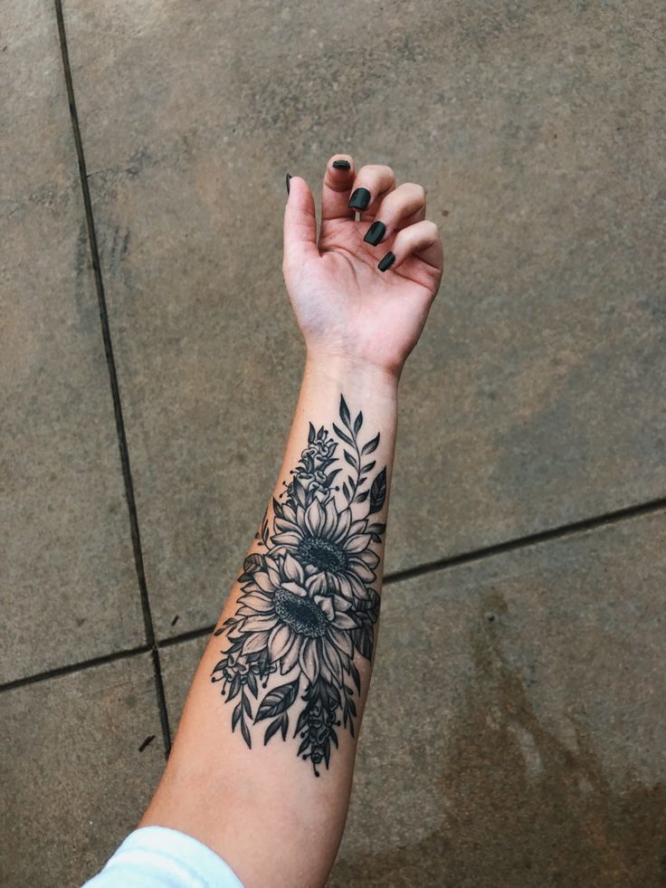 a woman's arm with a black and white flower tattoo on the left wrist