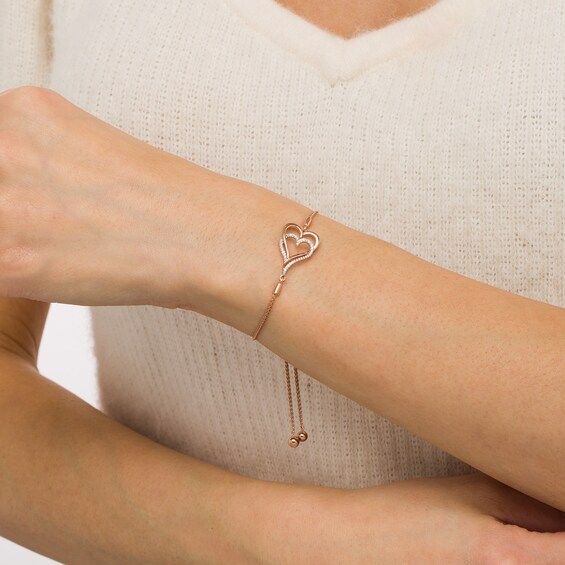 With double the love, this diamond heart bolo bracelet suits your romantic style. Created in sterling silver with 14K rose gold plate, this look features entwined sideways heart-shaped outlines - one polished, the other lined with sparkling diamonds. Captivating with 1/10 ct. t.w. of diamonds and a bright polished shine, this wheat chain bracelet adjusts up to 9.5 inches in length and secures with a bolo clasp and ball ends. Elegant Open Heart Bracelets For Mother's Day, Adjustable Fine Jewelry Heart Bracelet For Anniversary, Elegant Heart Bracelet For Mother's Day Anniversary, Elegant Open Heart Bracelet For Anniversary, Elegant Valentine's Day Heart Bracelet, Elegant Adjustable Open Heart Bracelet, Adjustable Rose Gold Heart Bracelet For Valentine's Day, Rose Gold Double Heart Jewelry For Formal Occasions, Elegant Adjustable Open Heart Jewelry