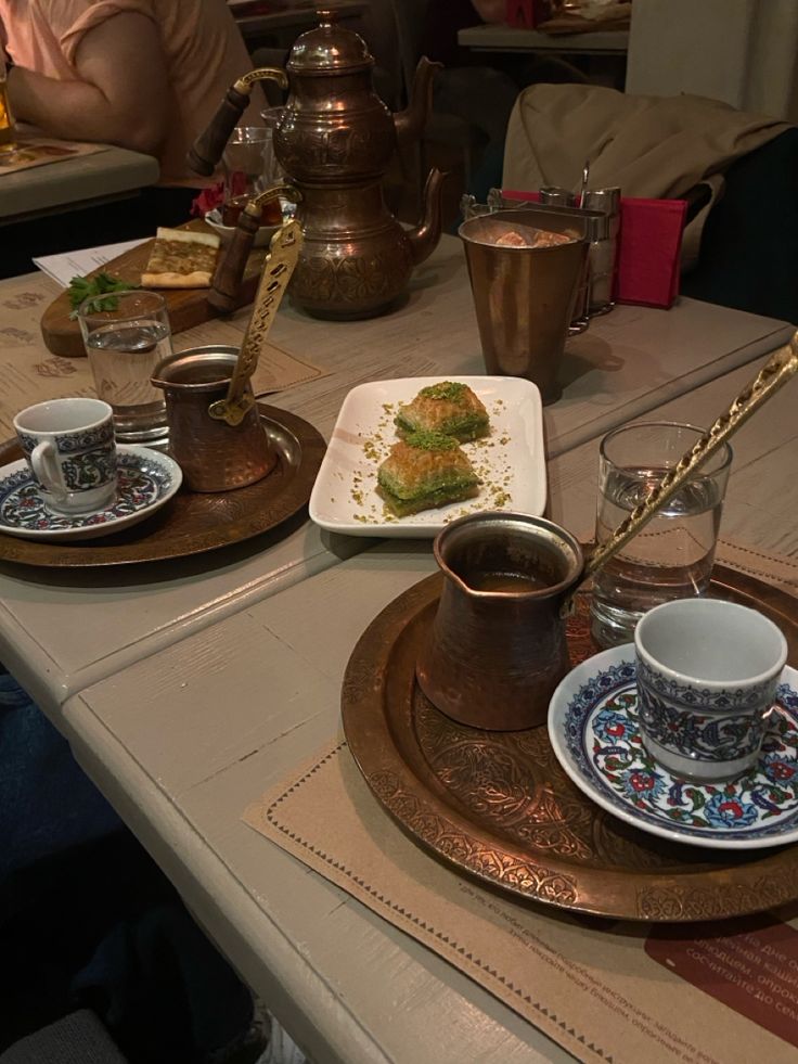 two plates with food on them sitting on a table next to cups and saucers