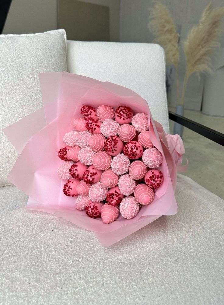 a bouquet of pink frosted cupcakes sitting on top of a white bed