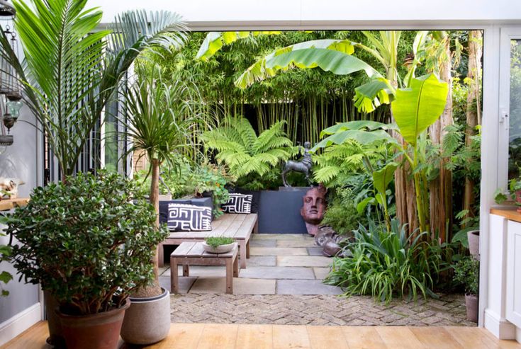 an outdoor area with plants and benches in the center, surrounded by greenery on either side