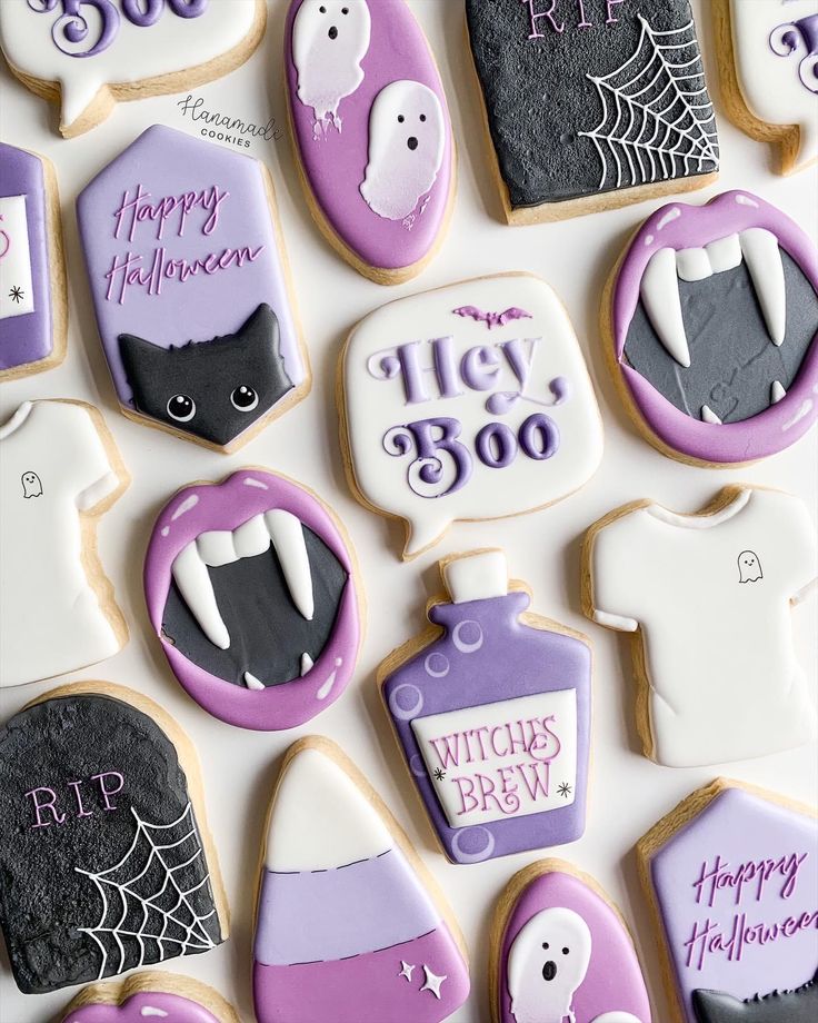 decorated halloween cookies with purple and white icing on a table top, all decorated in the same style