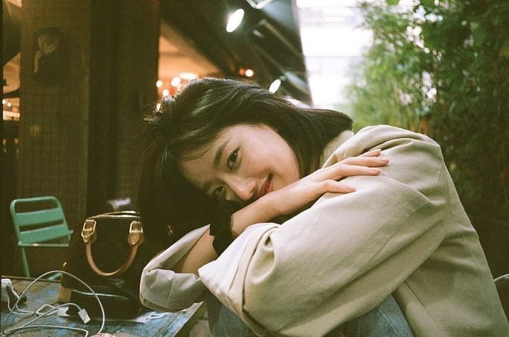 a woman sitting on a bench with her arms folded over her shoulder and looking at the camera