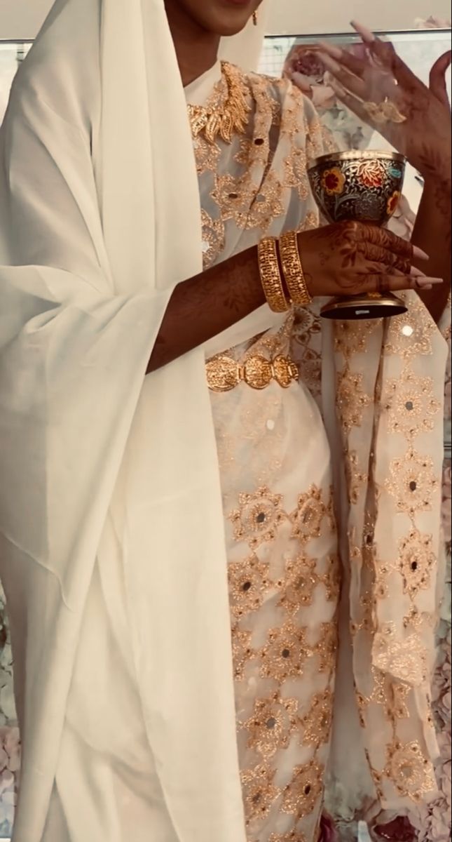 a woman dressed in white holding a cup