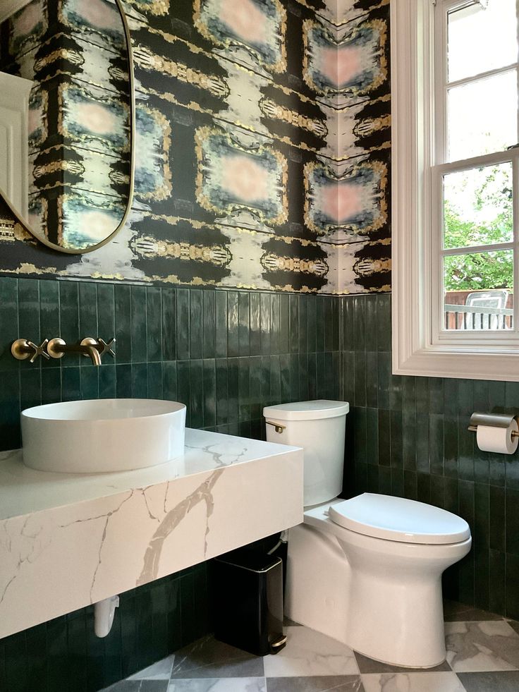 a white toilet sitting next to a sink in a bathroom under a mirror on top of a counter