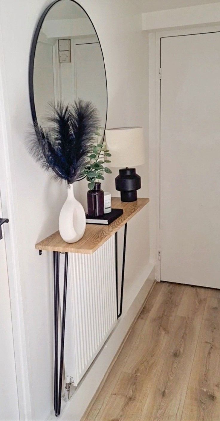 a mirror and some plants on a table in front of a white door with a wooden floor