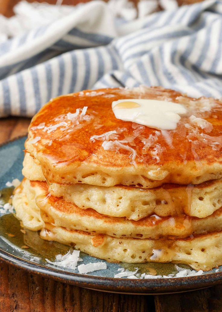 a stack of pancakes with butter and syrup on a blue plate next to a striped napkin