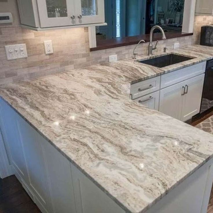 a kitchen with marble counter tops and white cabinets