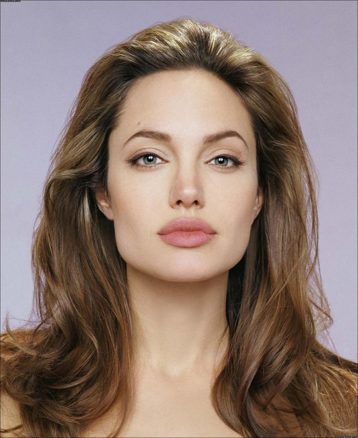 a woman with long brown hair and blue eyes is posing for the camera while wearing a necklace