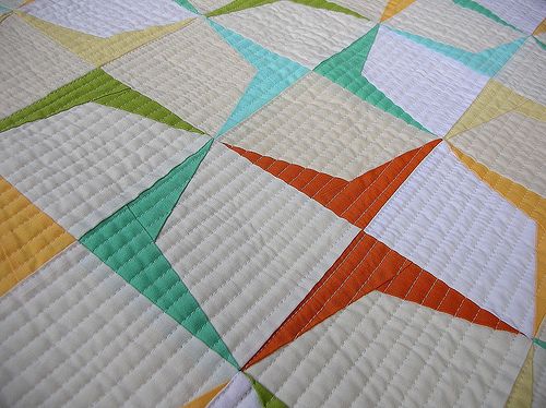 a quilted bed with an orange and green star on it