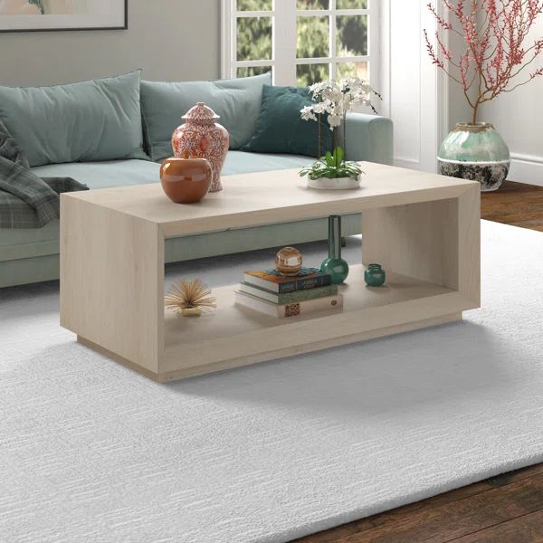 a living room with a couch, coffee table and vases on the floor in front of it