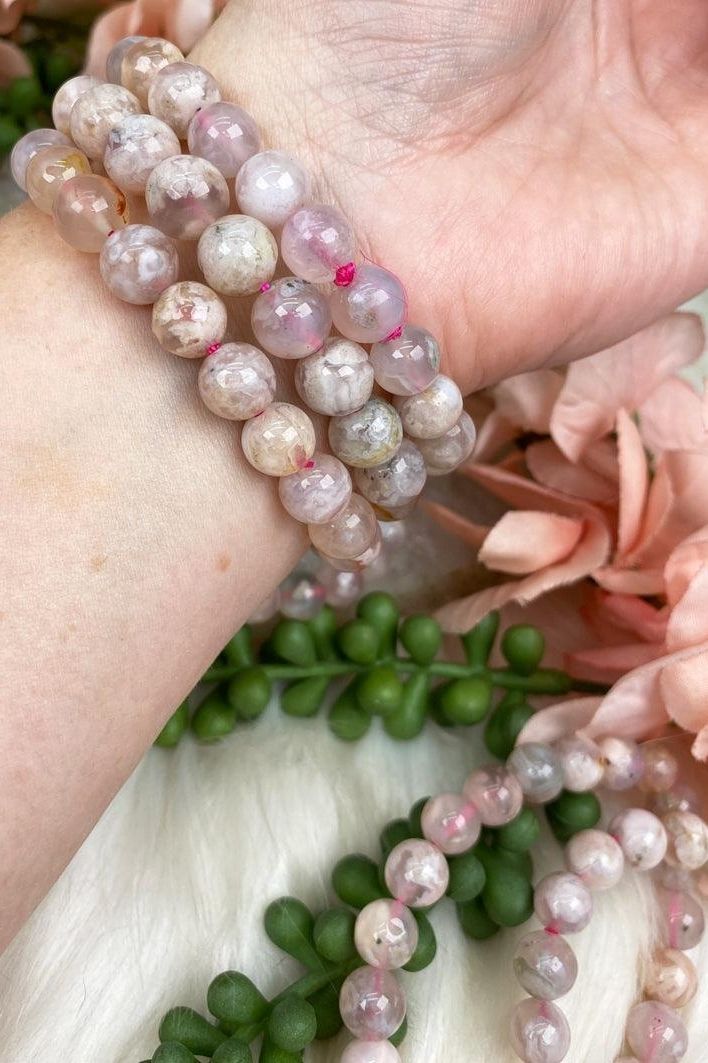 Adorable baby pink Flower Agate Bracelets with stones from Madagascar. Flower agate tends to have a mix of a transparent chalcedony mixed with the typical 'blossom' patterning throughout, and these are no different! They are truly all going to be unique. These are on a pink elastic to give a little more 'pink hue' overall. These are an 8mm bead, so they are a bit chunkier. Pink Natural Stones Stretch Bracelet For Meditation, Pink Stretch Bracelet With Natural Stones For Meditation, Pink Agate Crystal Bracelet As A Gift, Pink Gemstone Beads Bracelets For Meditation, Pink Agate Beaded Bracelets With Natural Stones, Pink Hand-strung Agate Jewelry, Hand-strung Pink Agate Jewelry, Pink Agate Jewelry With 8mm Beads, Handmade Pink Agate Bracelets