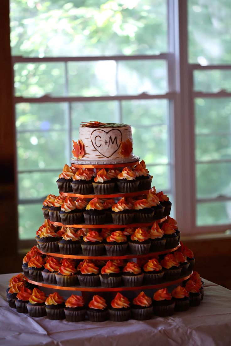 a wedding cake made out of cupcakes on top of a table in front of a window