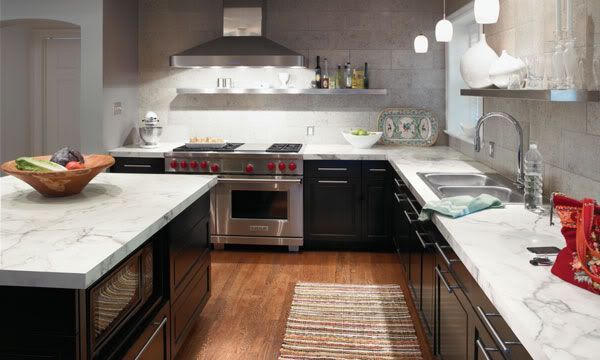 a modern kitchen with marble counter tops and stainless steel appliances, along with wooden flooring