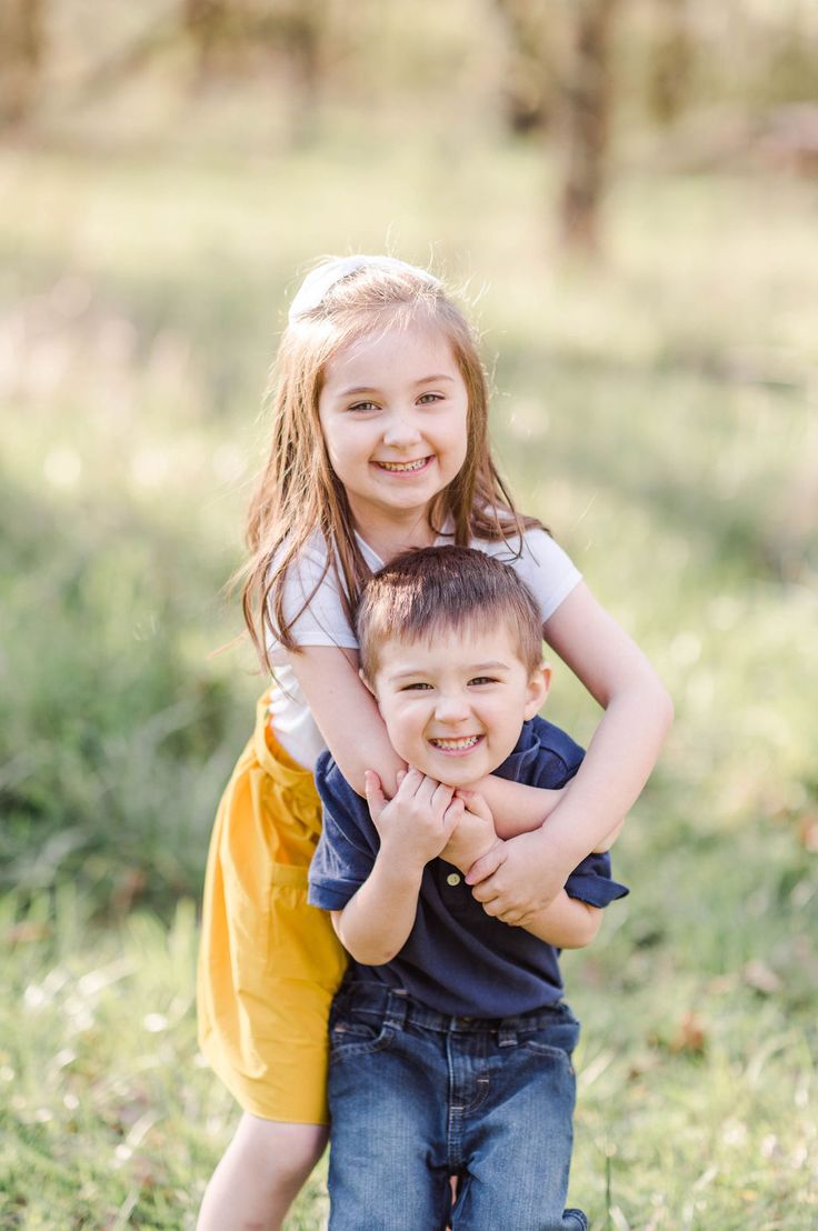 two young children hugging each other in the grass