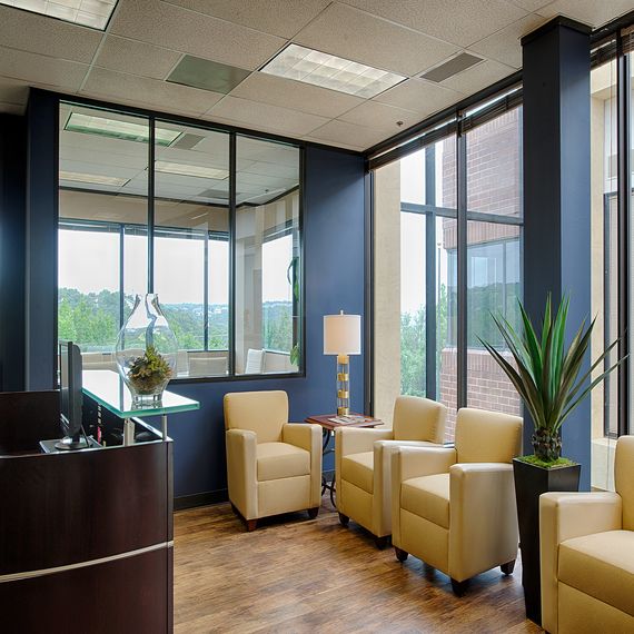 an office with chairs, desk and large windows