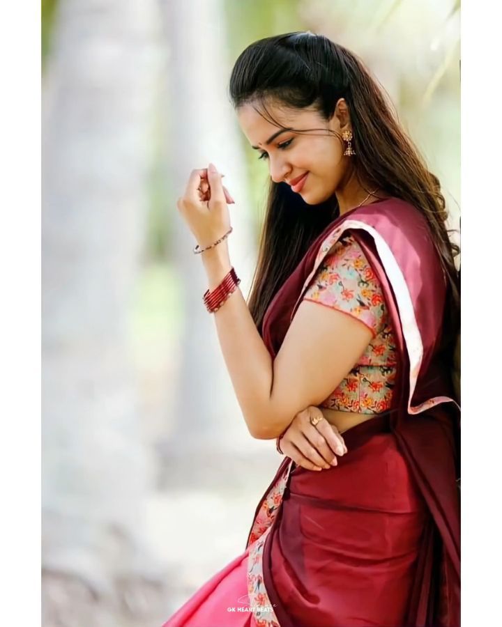 a woman in a red sari is smiling and holding her hand up to her face