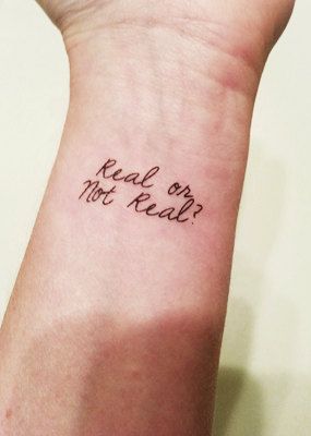 a person with a wrist tattoo that says real or not real