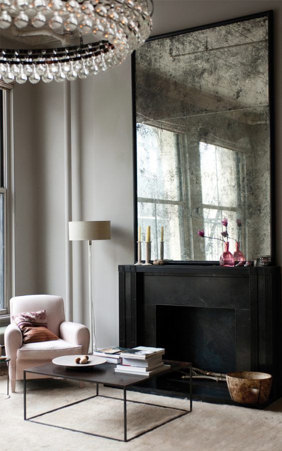 a living room filled with furniture and a large mirror on the wall over a fireplace