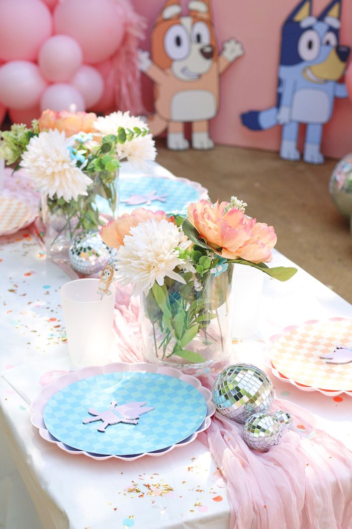 a table set up with plates and vases filled with flowers on top of it