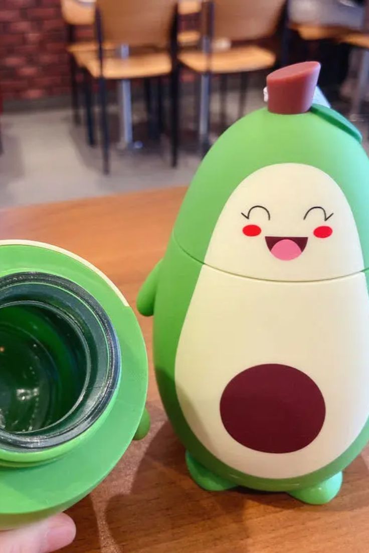 a green and white cup sitting on top of a wooden table next to a green container