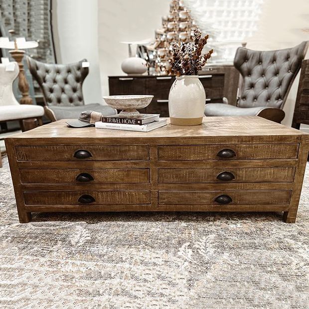 a coffee table with two chairs and a vase on it in a room filled with furniture