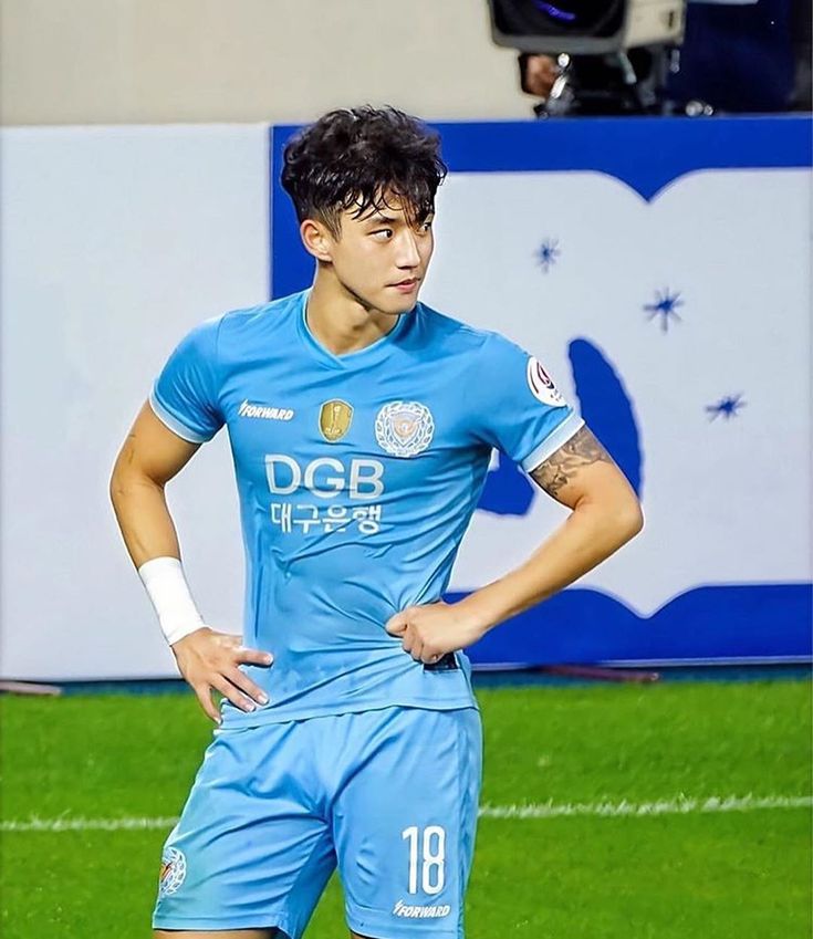 a man standing on top of a soccer field wearing a blue uniform and holding his hands on his hips