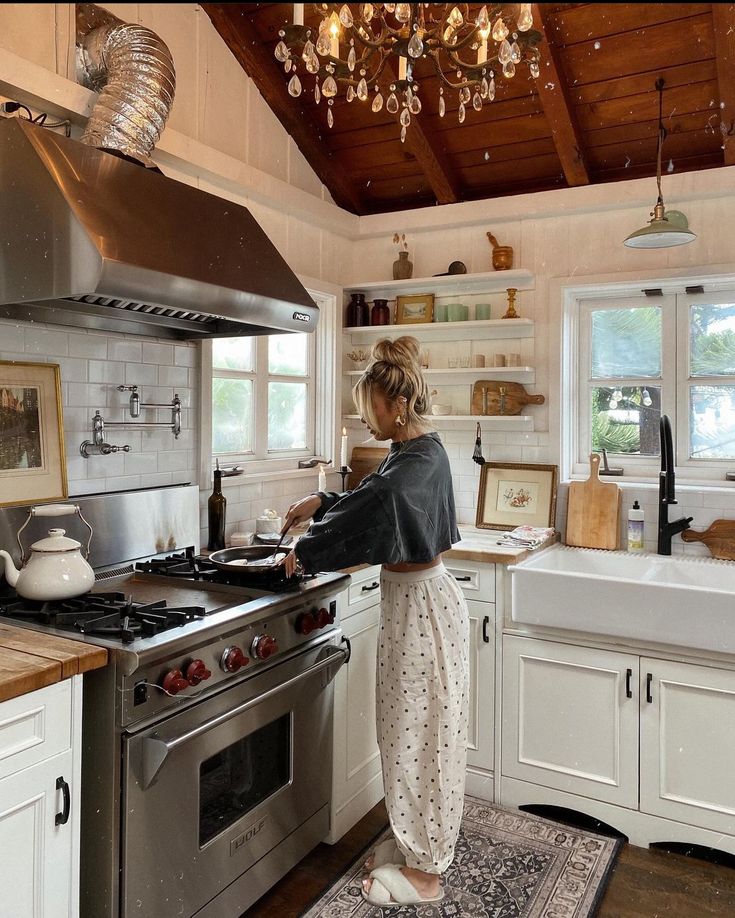 a woman standing in a kitchen preparing food on top of a stove next to a sink