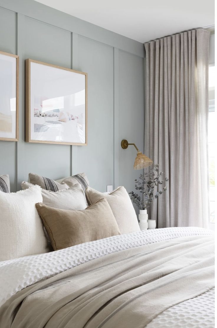 a bed with two framed pictures on the wall above it and pillows in front of them