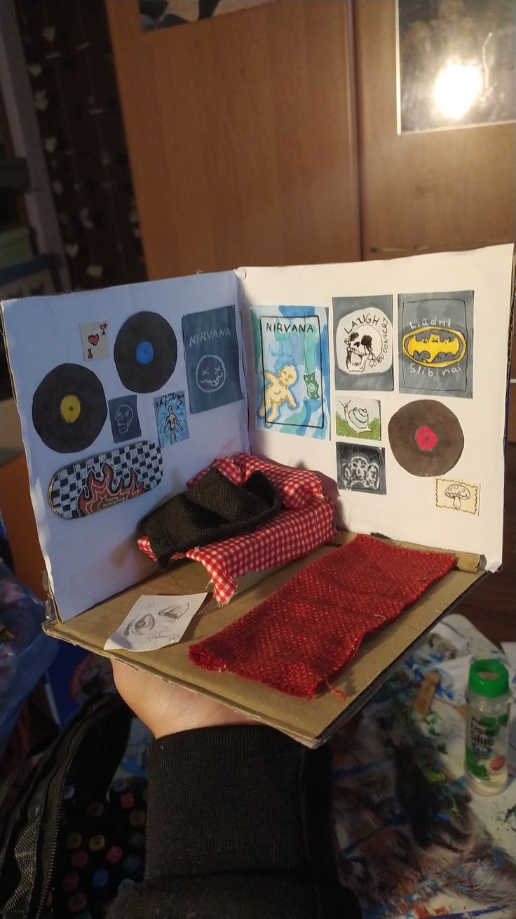 someone is holding up an open book with records on it and various other items in the box