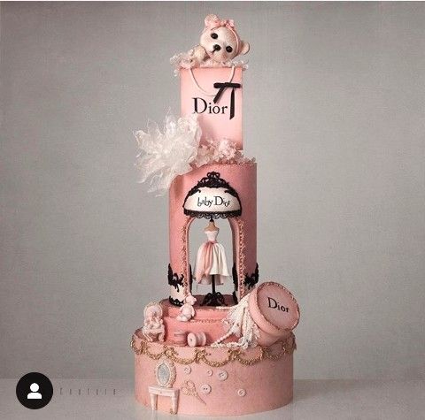 a three tiered cake with a teddy bear on top and other items around it