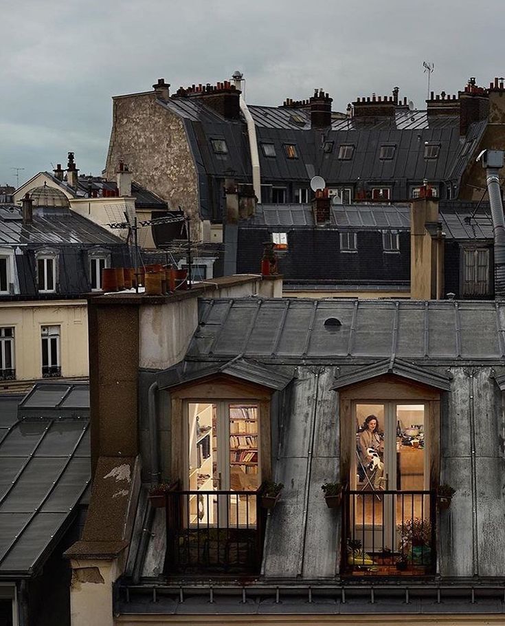 an apartment building with two people standing on the balcony and looking out at the city