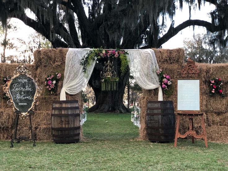 an outdoor ceremony with hay bales and flowers on the altar, chalkboard sign