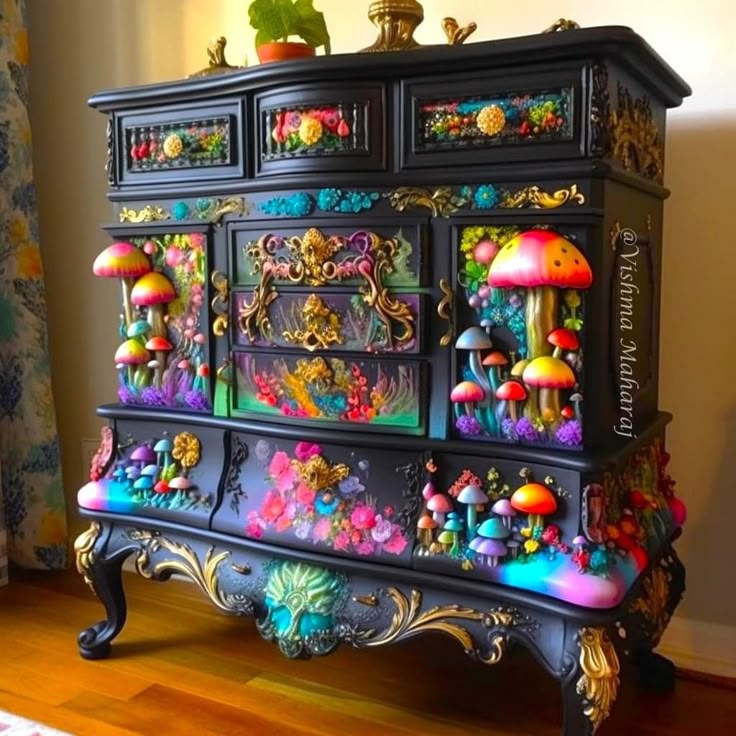 an ornate dresser with many colorful decorations on the top and bottom drawers, painted black